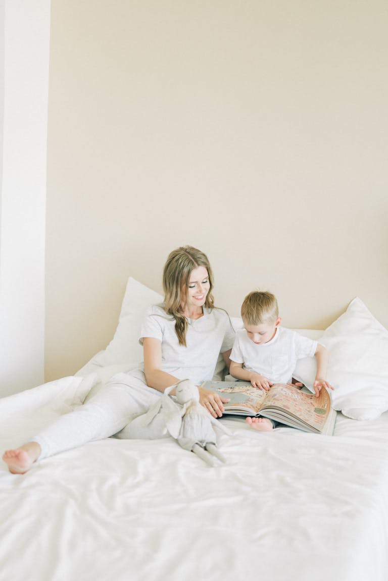 A mother and child share a tender reading moment on a cozy bed, embracing warmth and togetherness.