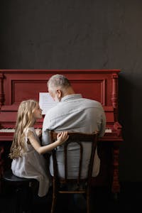 A young girl and her grandfather enjoying a piano session, symbolizing family bonding and music learning.