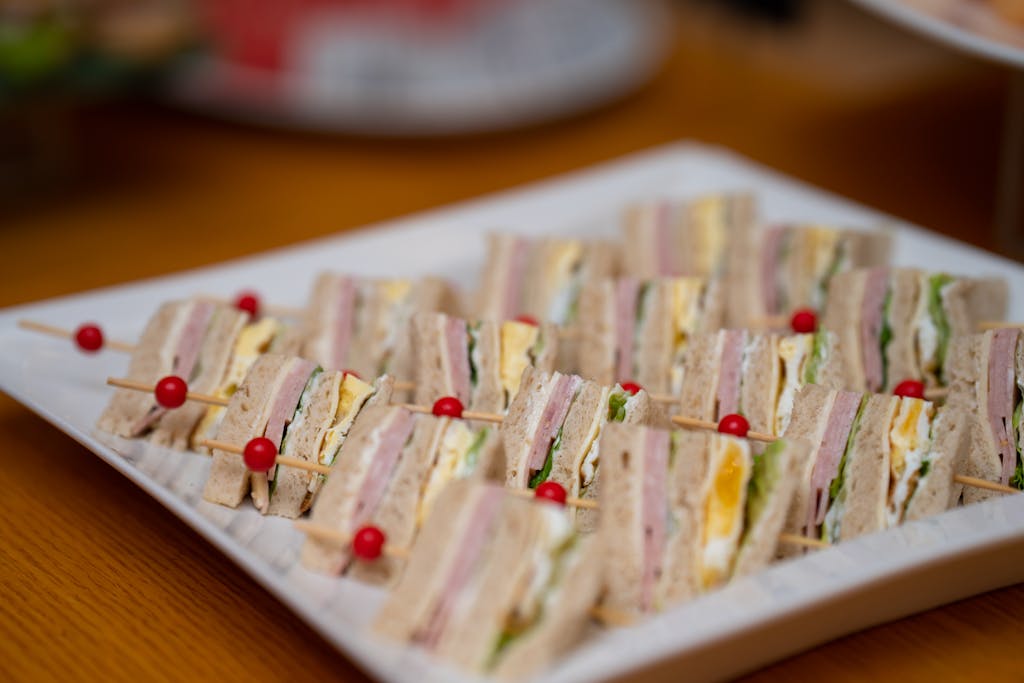 Delicious gourmet sandwich skewers with assorted meats, cheese, and fresh vegetables on a plate.