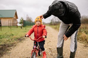A father and child enjoy quality time biking outdoors on a countryside path in autumn.